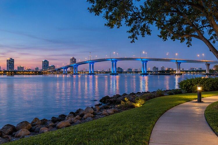 An illustrative riverfront with a bridge and blue evening sky