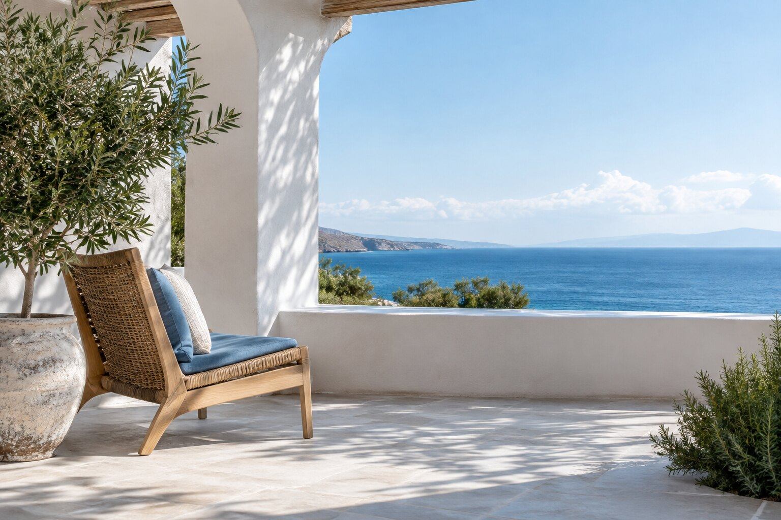 Una terraza blanca a la sombra con una silla y una planta